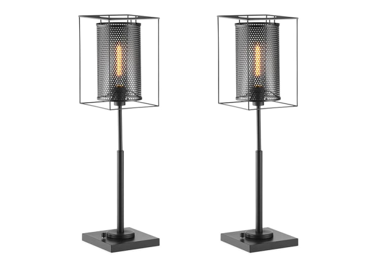 Pair of black metal table lamps with industrial design, featuring perforated cylindrical shades inside open cube frames and square bases.