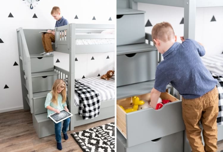 Children interacting with a gray wooden bunk bed with built-in storage stairs, featuring a striped bedspread and black-and-white rug.