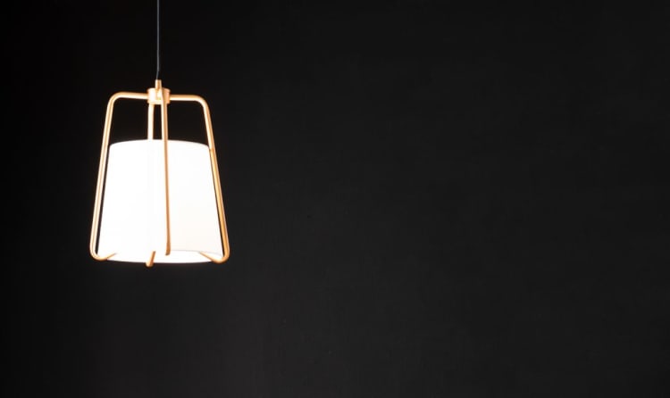 Modern hanging pendant light with a white cylindrical shade and gold metal frame against a black background, ideal for contemporary interior lighting.