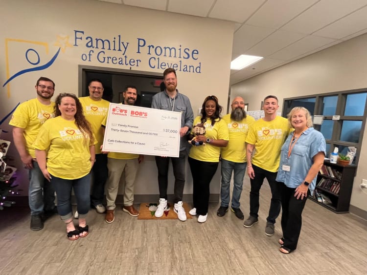 Group of volunteers at Family Promise of Greater Cleveland holding a large $37,000 check from Bob’s Outreach for Café Collections for a Cause fundraising event.
