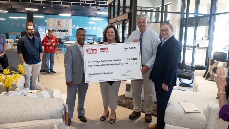 Group of people holding a large check from Bob's Discount Furniture dated Sept. 1, 2023, for $2,500 to Orange Community Services for Random Act of Kindness.