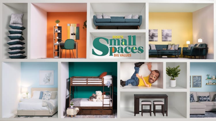 Compact living space display with stacked cushions, orange accent wall workspace, teal sofa, yellow lounge area, light blue bedroom, wooden bunk beds with stuffed animals, dark wood dining set, and decorative plants. Central text reads: "BOB'S Small Spaces BIG VALUES."