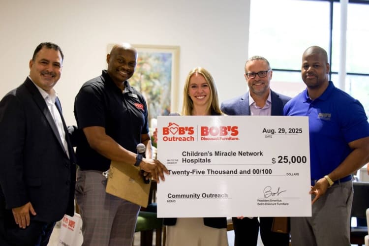 Five people holding a large check dated Aug. 29, 2025, from Bob’s Discount Furniture for $25,000 to Children’s Miracle Network Hospitals for community outreach.