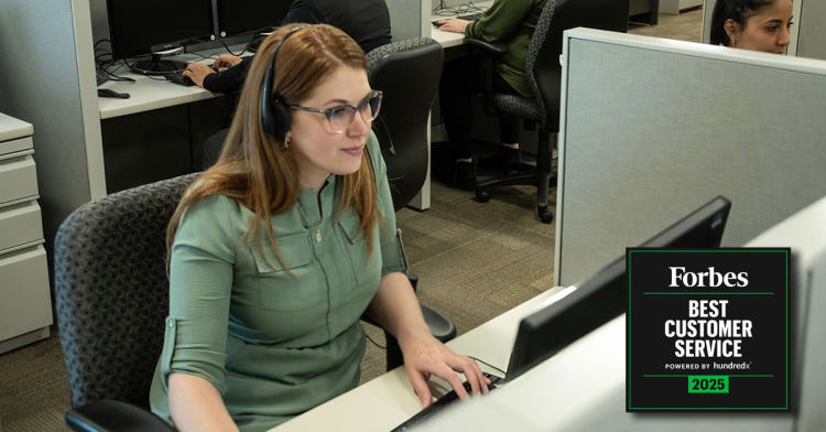 Woman wearing a headset working at a computer in an office cubicle with a Forbes Best Customer Service 2025 award badge displayed.