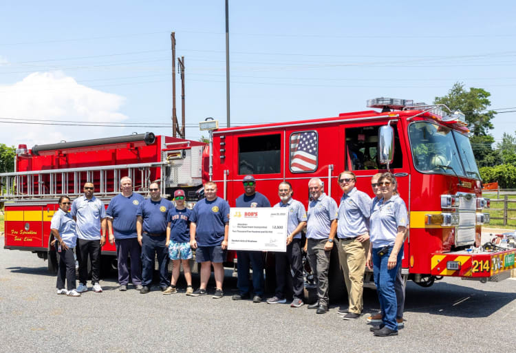 Group of firefighters standing in front of a red fire truck holding a large check from Bob's for $2,500 to Aberdeen Fire Department, dated June 25, 2023.
