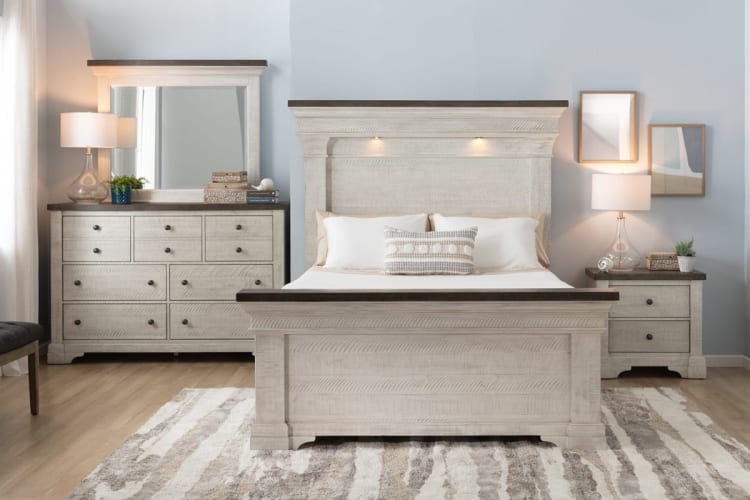 Bedroom set with light wood finish bed frame, matching dresser with mirror, and nightstand, featuring dark wood tops and modern lamps.