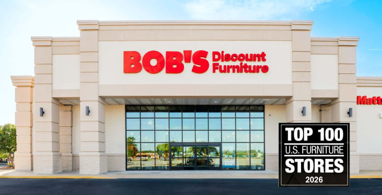 BOB'S Discount Furniture storefront with large glass windows and beige exterior. Text on image: "TOP 100 U.S. FURNITURE STORES 2026."