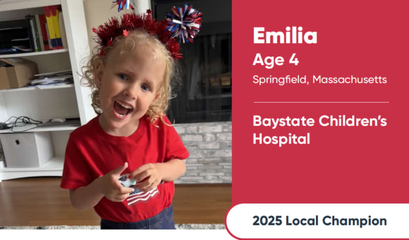 Young child wearing a red shirt with an American flag design and festive red, white, and blue headband. Text reads: Emilia, Age 4, Springfield, Massachusetts, Baystate Children’s Hospital, 2025 Local Champion.