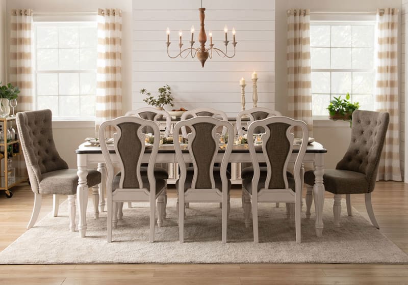 Dining room set with a rectangular white wood table and eight upholstered chairs in gray fabric, featuring button-tufted backs and beige striped curtains.