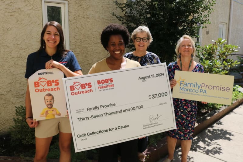 Four people holding a large $37,000 check dated August 12, 2024, from Bob’s Discount Furniture to Family Promise for Café Collections for a Cause. One person holds a Bob’s Outreach sign. Family Promise Montco PA logo and tagline "An Interfaith Response to Homelessness and Hunger" are visible.
