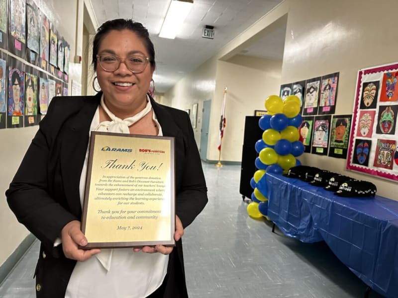 Person holding a thank you plaque from LA Rams and Bob's Discount Furniture, appreciating support for educators' lounge, dated May 7, 2024.