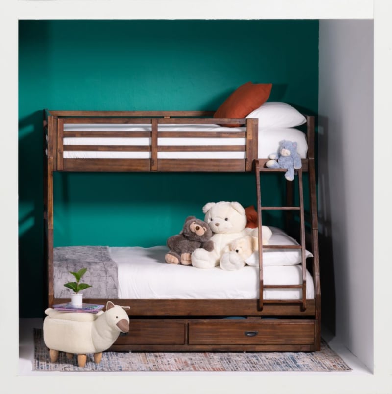 Wooden bunk bed with dark brown finish, white bedding, orange pillows, and stuffed animals, set against a teal wall with a patterned rug.