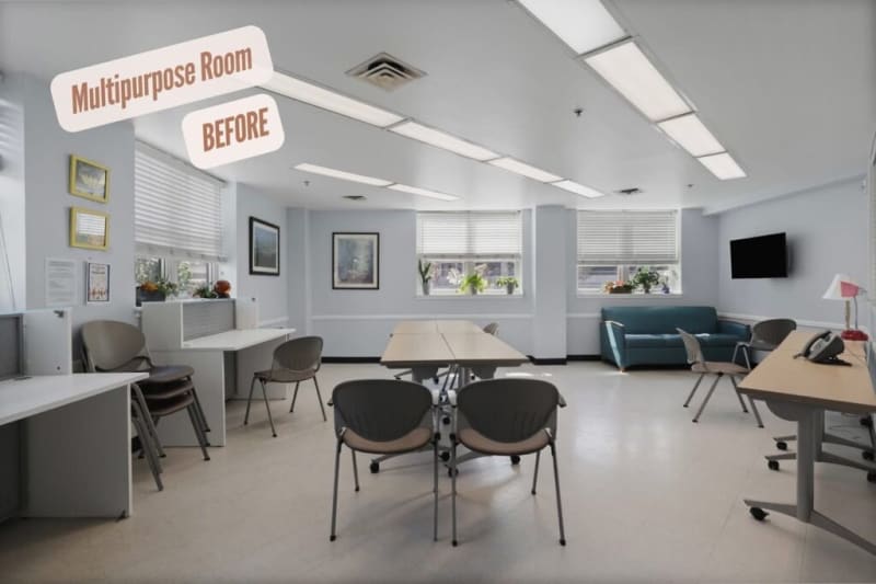 Multipurpose room before setup with light blue walls, fluorescent ceiling lights, multiple chairs, tables, a teal sofa, wall art, and window blinds.