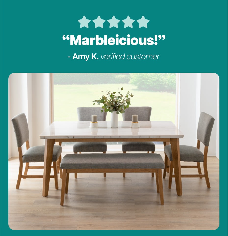 Five-star rating with the text “Marbleicious!” by Amy K., verified customer, above a modern dining set featuring a white marble tabletop, wooden legs, gray upholstered chairs, and a matching bench on light wood flooring.