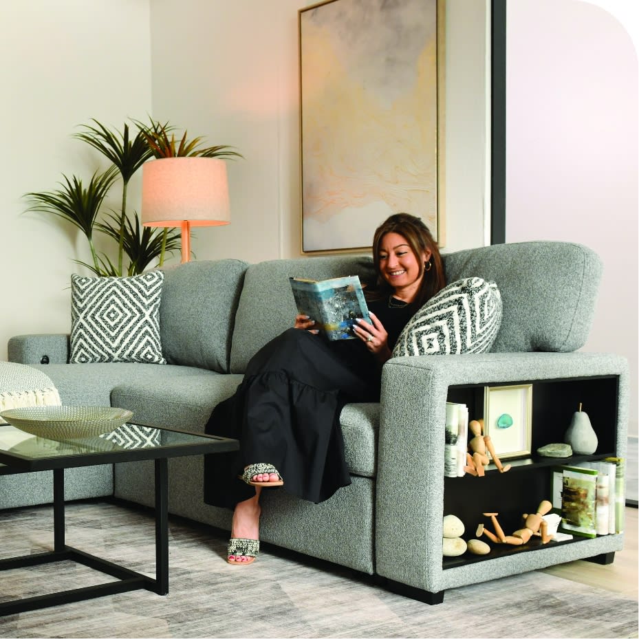 A cozy gray sectional sofa with storage and a woman reading a book.