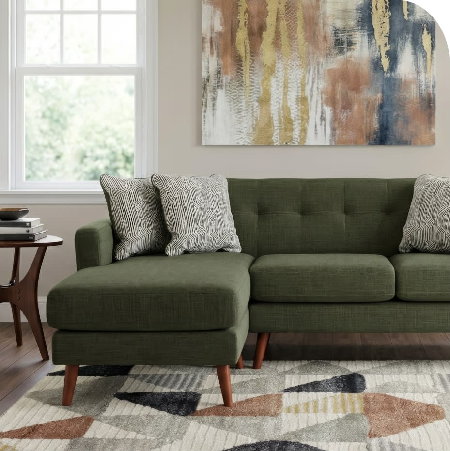 Modern olive green fabric sectional sofa with tufted back cushions, wooden legs, patterned throw pillows, and a mid-century style side table.