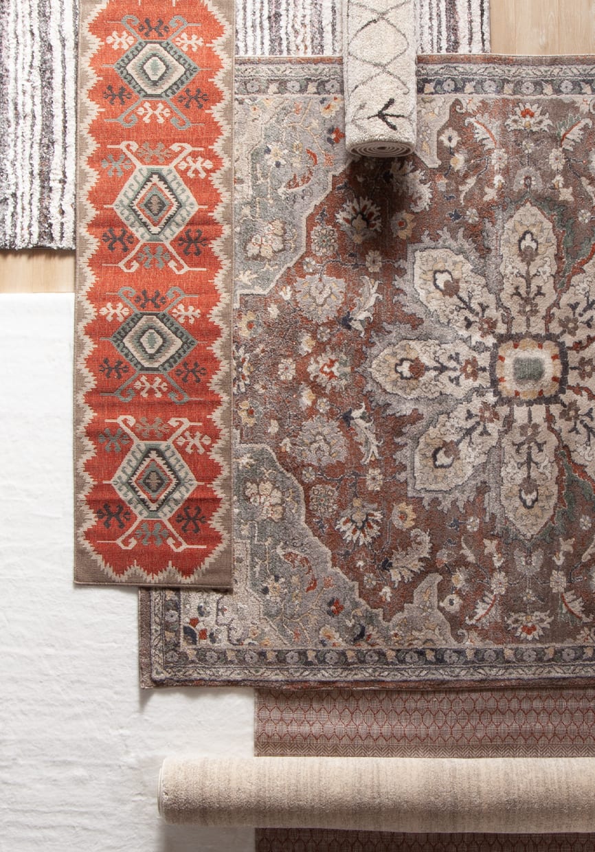 7 rugs overlapping each other in a variety of colors and patterns