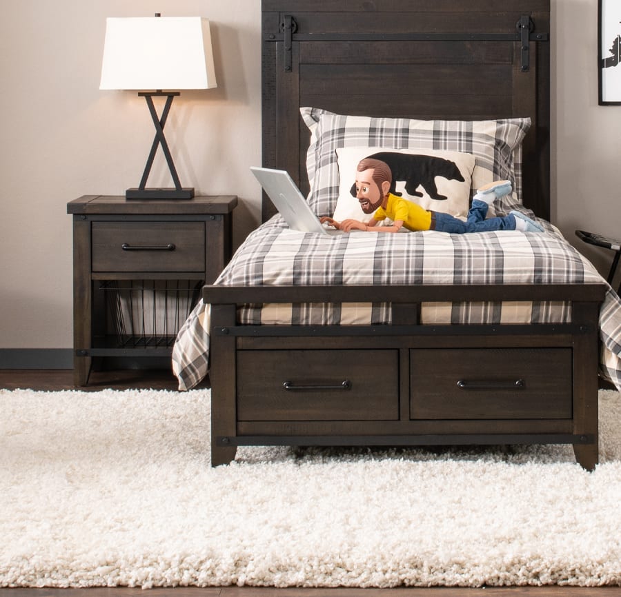 Dark gray twin bedroom set with little Bob laying on top of the bed. Bed is on a white plush area rug.