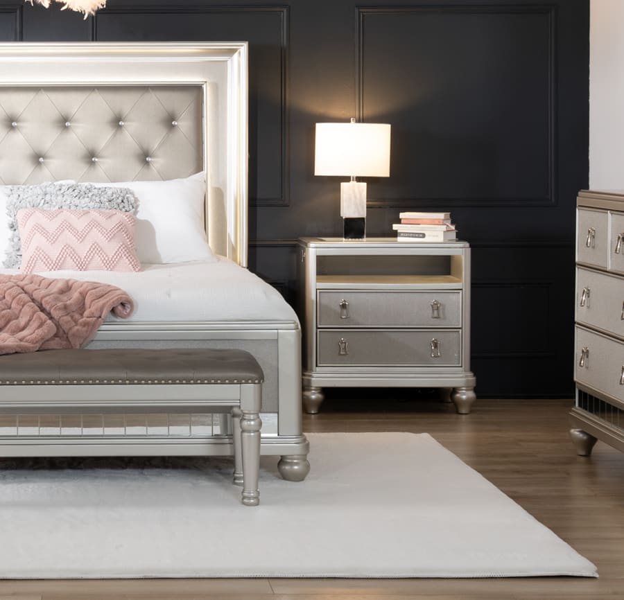 White and gray glam bed on a white large area rug. Featuring the matching nightstand, dresser and bench. White bedding with accent pink pillow and throw blanket.