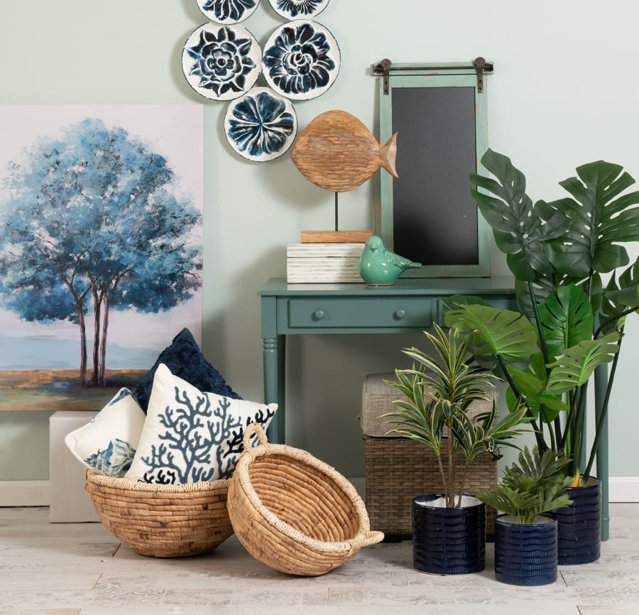 Assortment of accent storage, accent pillows, plants, wall art and decor items with tones of blue and sea green.