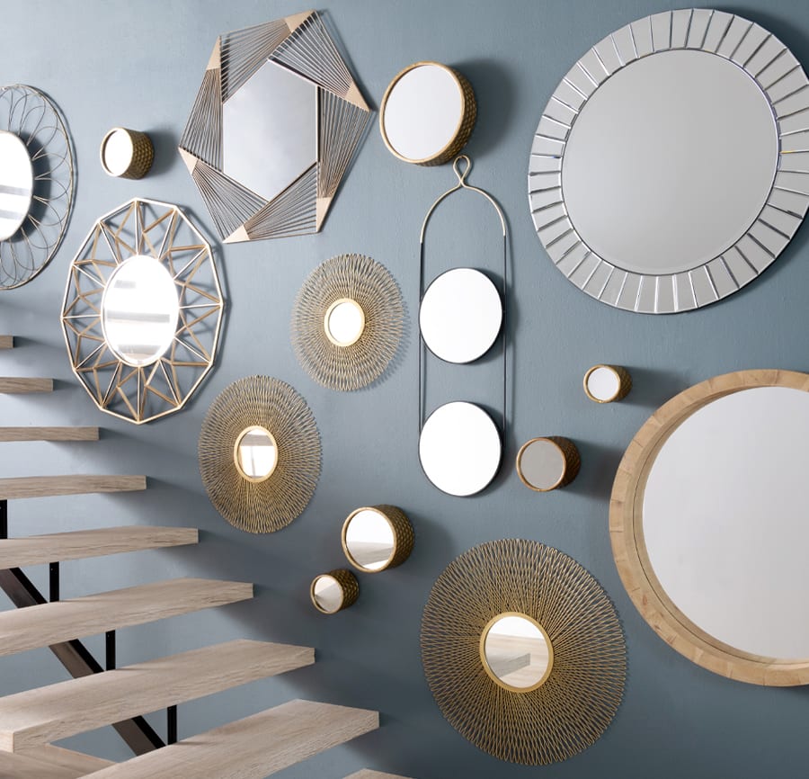Dark gray blue wall with an assortment of wall mirrors with a flight of stairs.