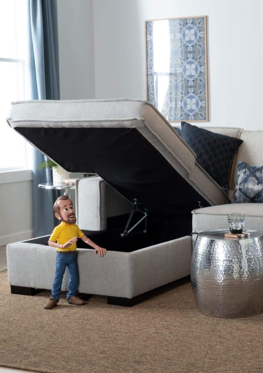 Beige left arm sectional chaise storage open with little Bob staring into it.