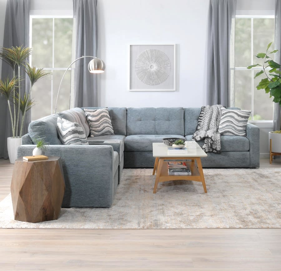Gray modular sectional with accent pillows and throw blanket, wooden prism side table, and coffee table.