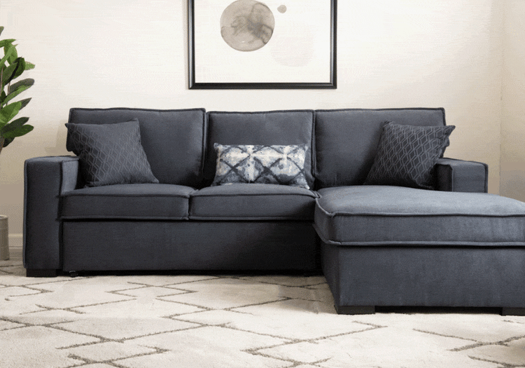 Dark gray fabric sectional sofa with chaise lounge, featuring plush cushions and patterned throw pillows, shown in a modern living room setting.