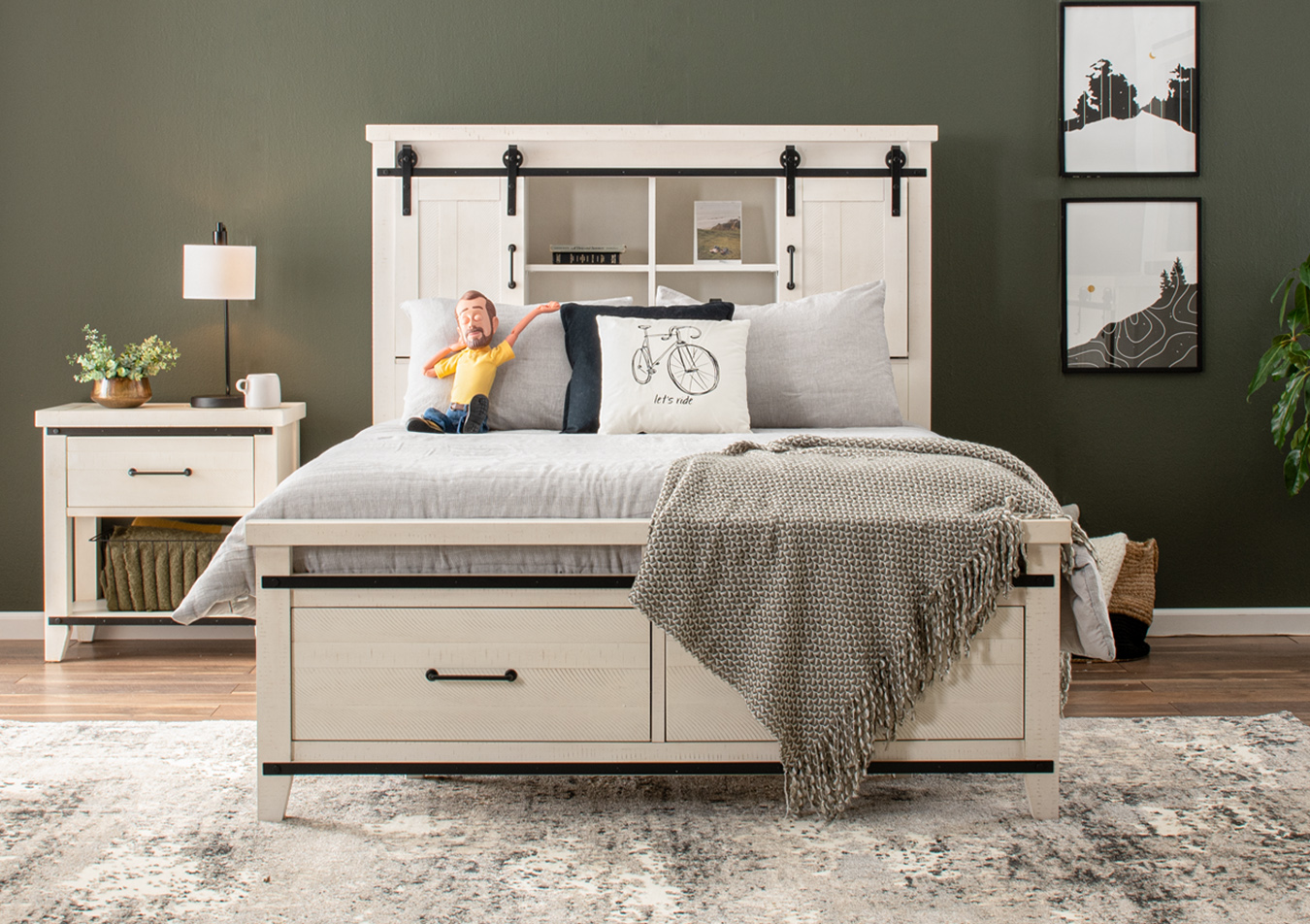 White with black hardware two-tone bedroom set with a bed featuring an industrial farmhouse door bookcase headboard, and nightstand with drawer on an abstract beige rug and simple black table lamp.