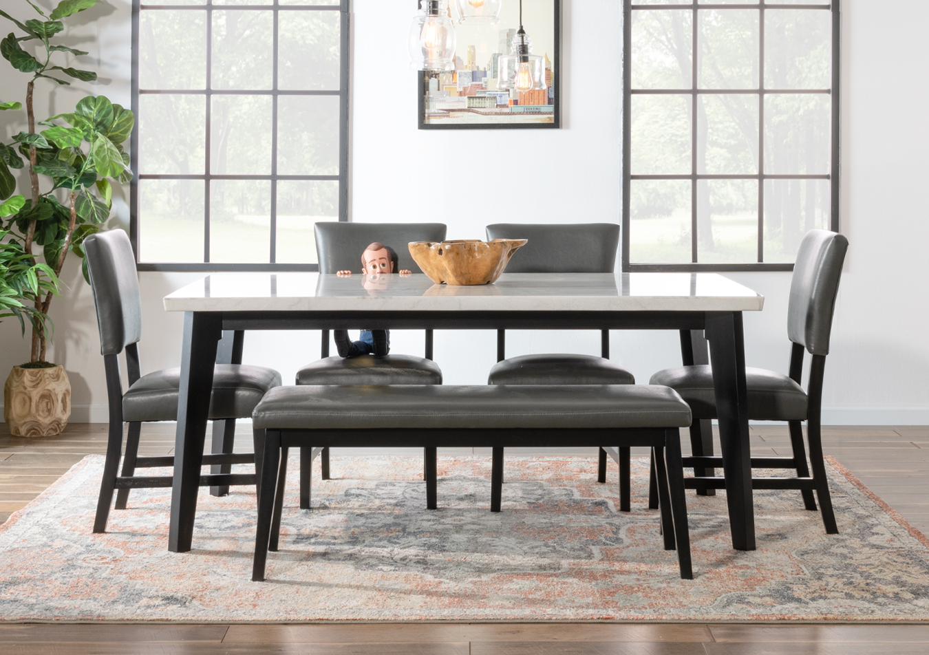 Dining room with white marble rectangular dining table with black base, 4 gray faux leather panel back dining chairs, gray faux leather upholstered dining bench, beige multi colored vintage area rug.