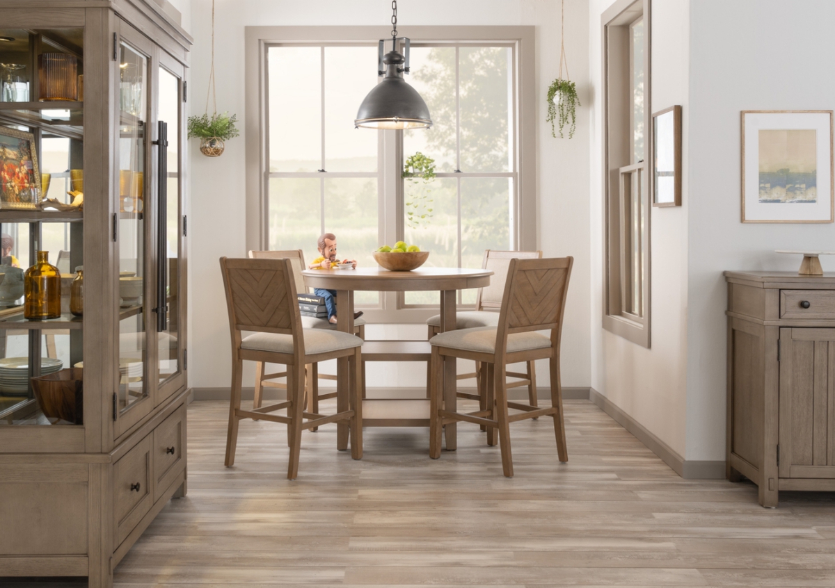Small dining room with Light brown counter height round dining table with 4 brown and beige panel back counter height stools.  4 drawer server and tall 2 glass door china cabinet flank the space.