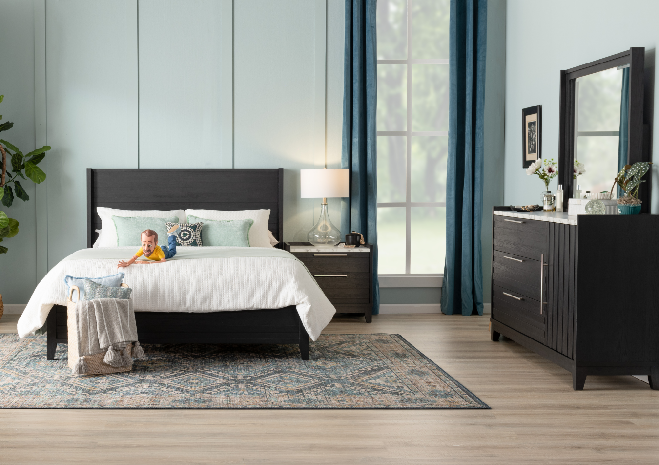 Charming espresso wooden bedroom set featuring faux marble tops with bed, 3 drawer dresser with mirror, and 2 drawer nightstand, sitting on a blue and light brown geometric rug, with decorative glass lamp and pillow bin.