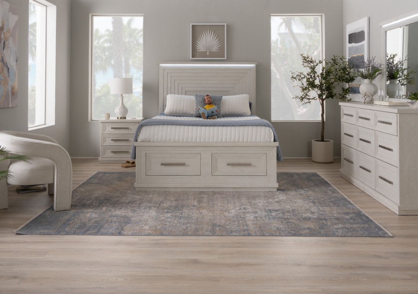 Contemporary bedroom set in white featuring a 2 drawer storage bed with white comforter and LED headboard, 9 drawer dresser with beveled mirror and LED lighting, and 3 drawer nightstand with white lamp, all against a gray wall.