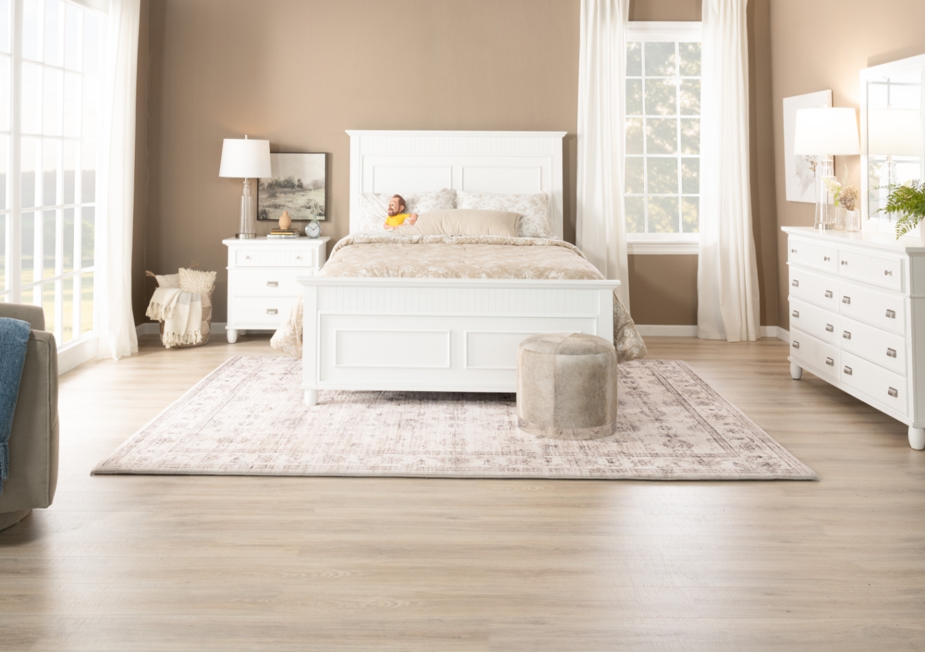 Classic white bedroom set with silver hardware featuring bed, 8 drawer dresser with mirror, and 3 drawer nightstand, sitting on a white oriental area rug with beige throw blanket and gray and white accent pillows.