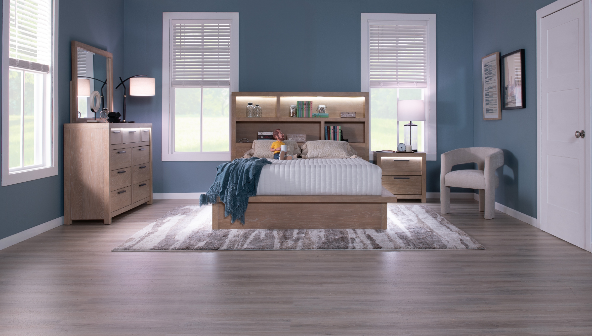 Contempory natural finish bedroom set, showcasing a storage headboard bed with LED lighting, a 9 drawer dresser and mirror with lighting, and a 2 drawer nightstand with lighting, all against a gray-blue wall and on a gray wood floor with area rug.