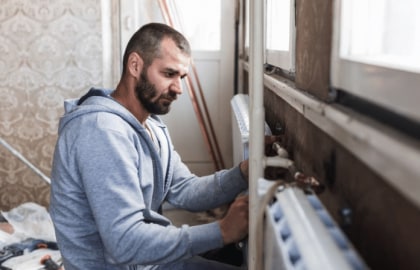 Homme artisan remplace radiateur logement ancien