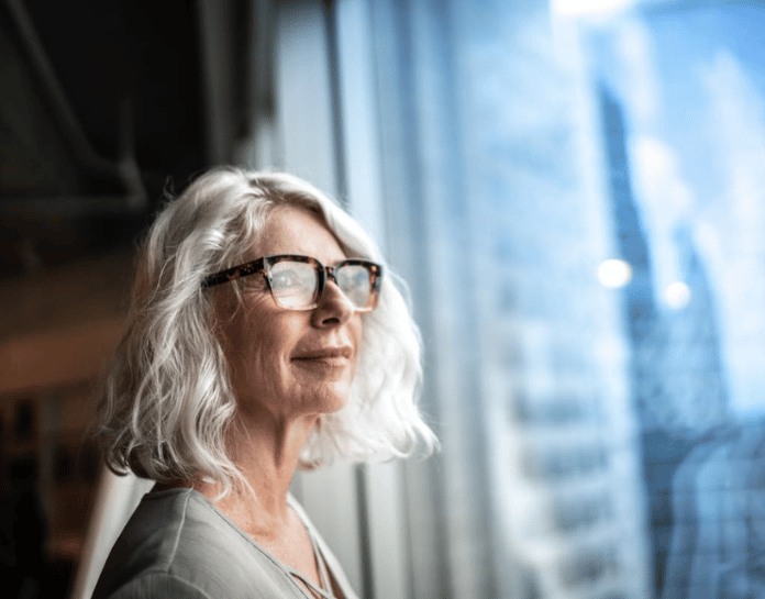 femme cheveux blanc regarde par la fenetre