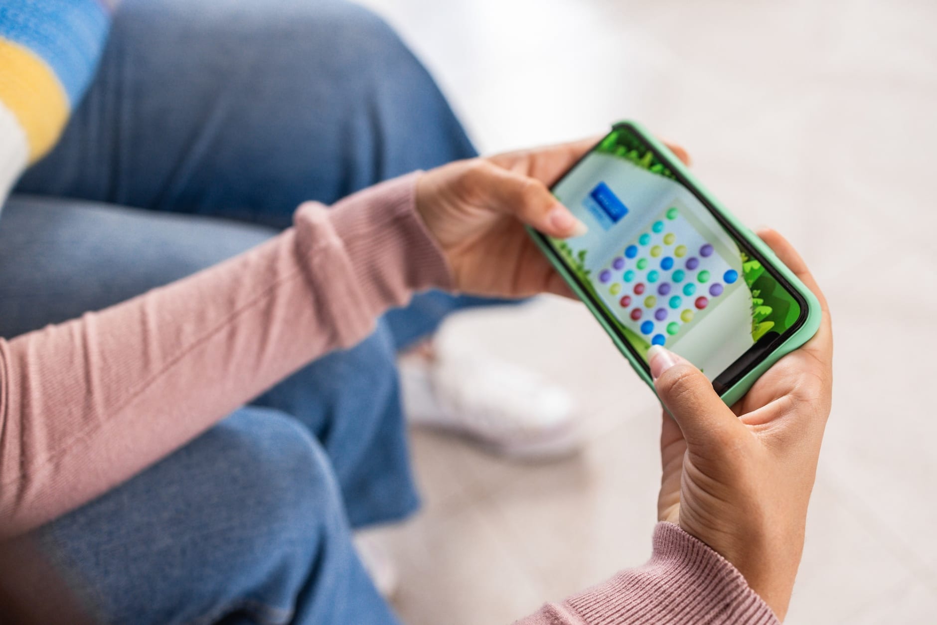 Young girl playing video game on mobile phone app - Focus on right hand