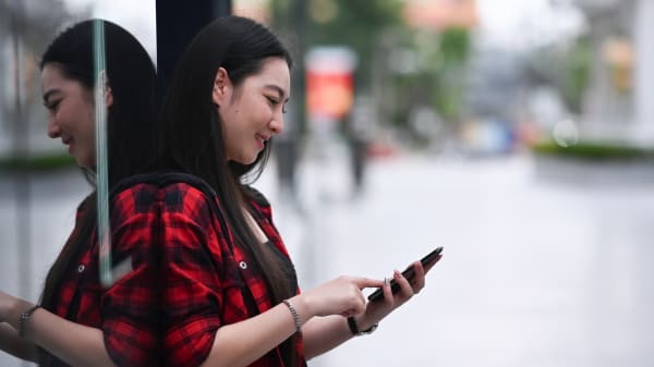 Young Asian woman using smartphone while standing in the shopping district of a city.