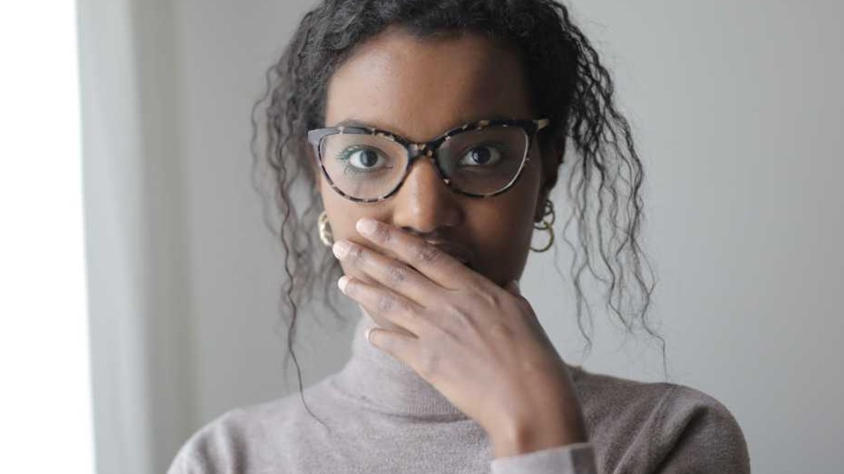 Photo of woman with hand over mouth - she told a secret and is worried.