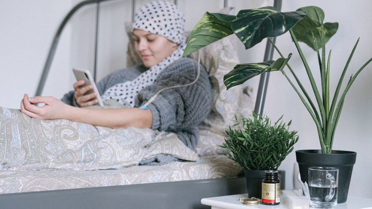 Swedish team creates drug that burns leukemia cells A woman undergoing cancer treatment relaxes in bed using her phone, surrounded by plants.