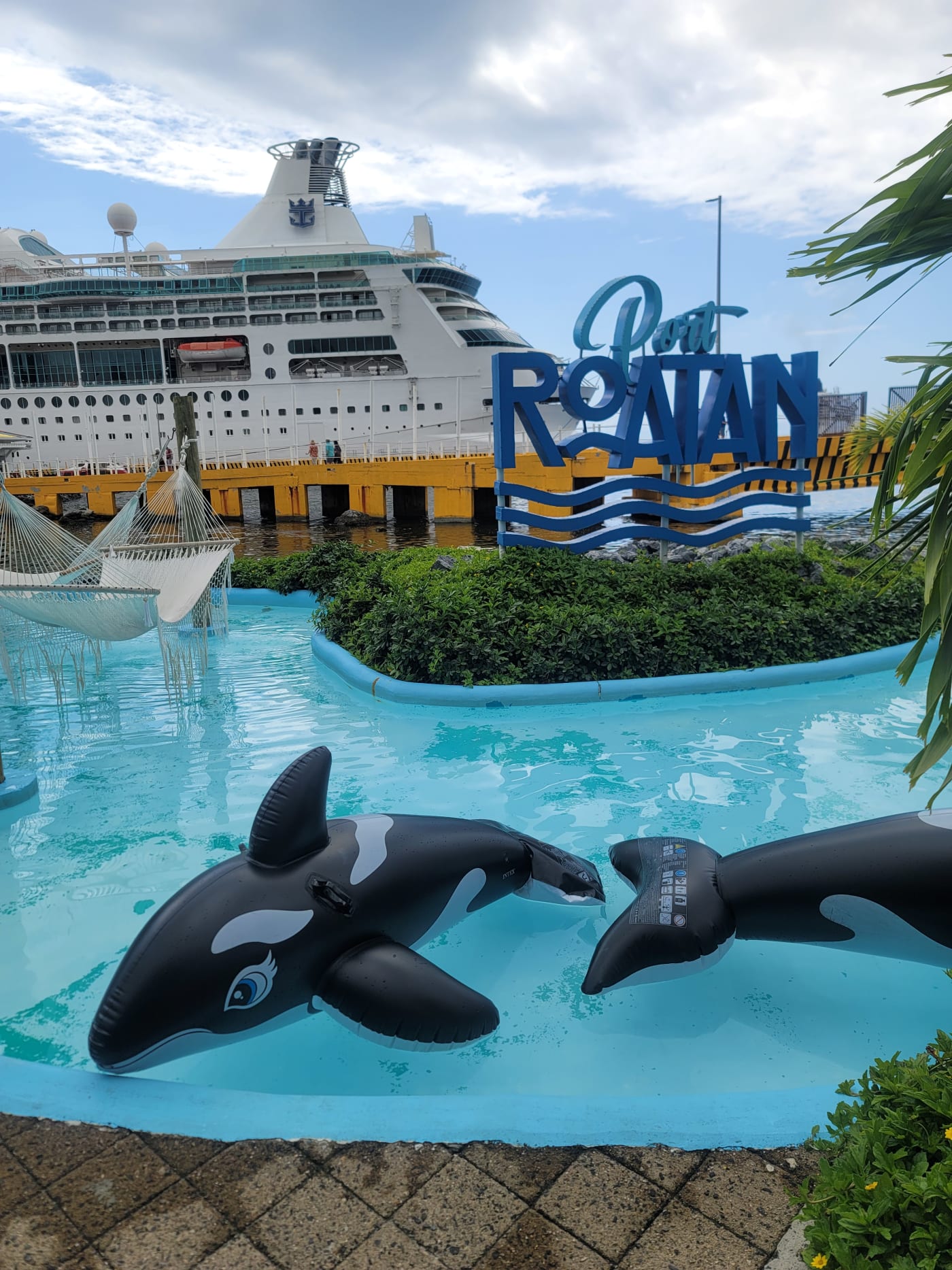 The Port Roatán sign at the Coxen Hole cruise port, with a cruise ship docked behind