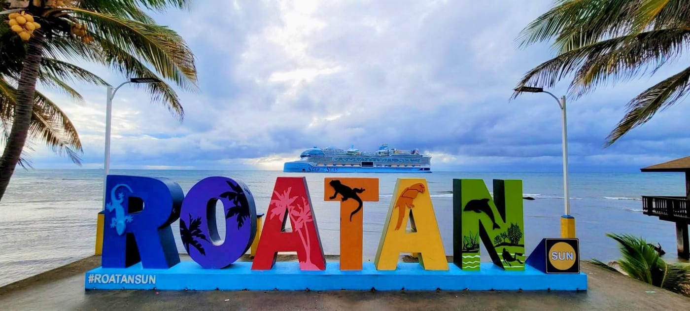 The Roatán sign with a cruise ship behind it