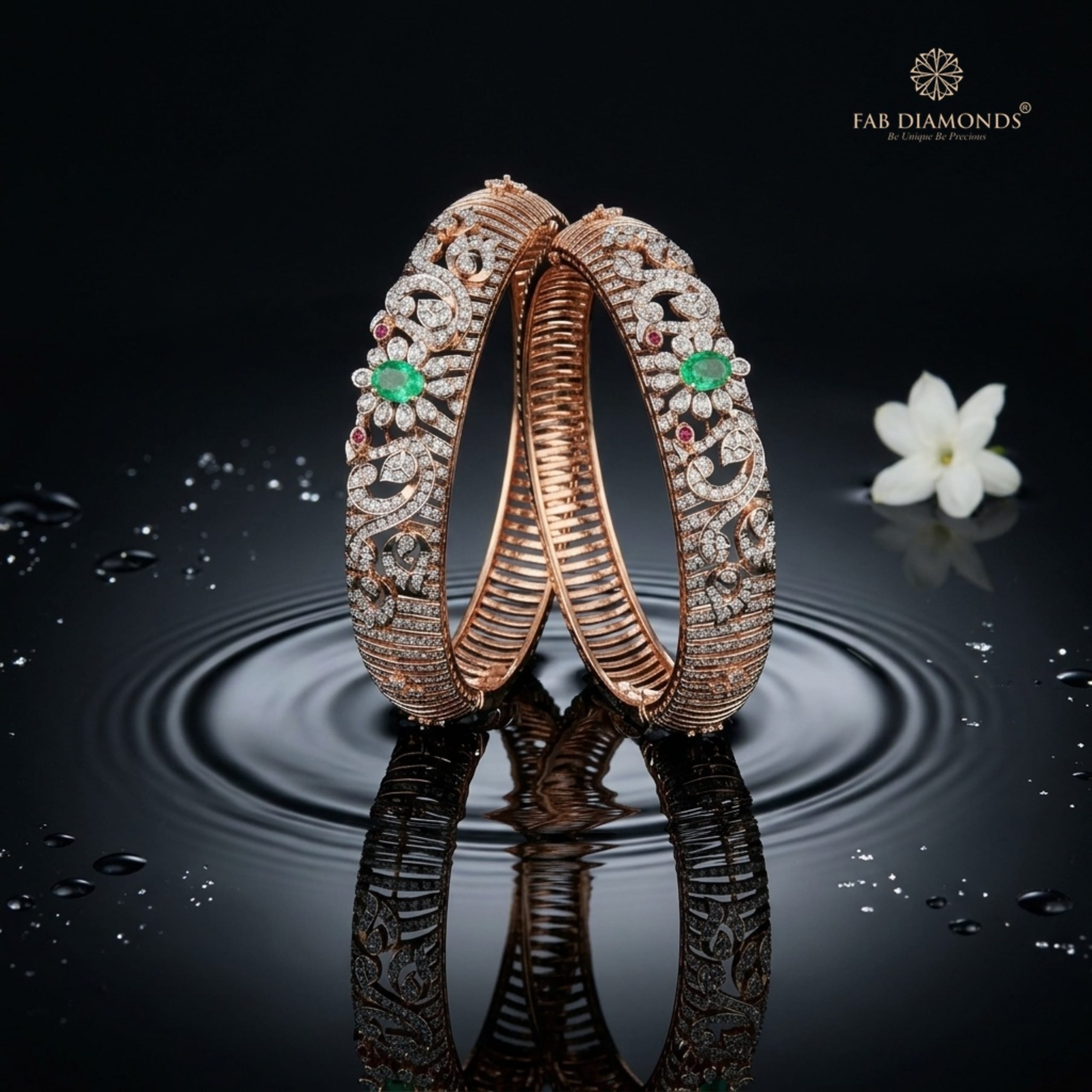 A pair of 18KT gold bangles with floral diamond work, emerald centres and ruby accents