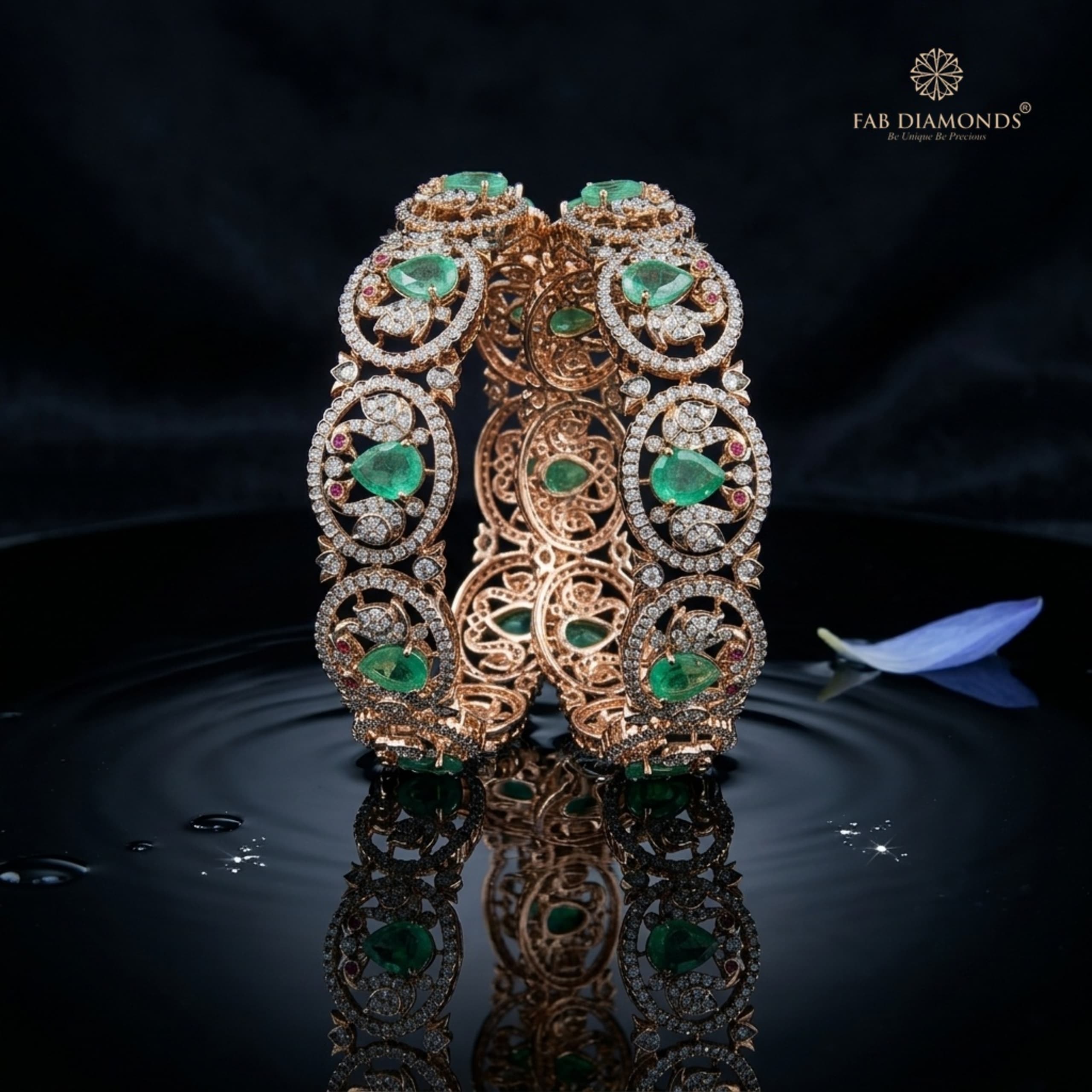 A pair of 18KT gold bangles with large oval emeralds in diamond cluster halos