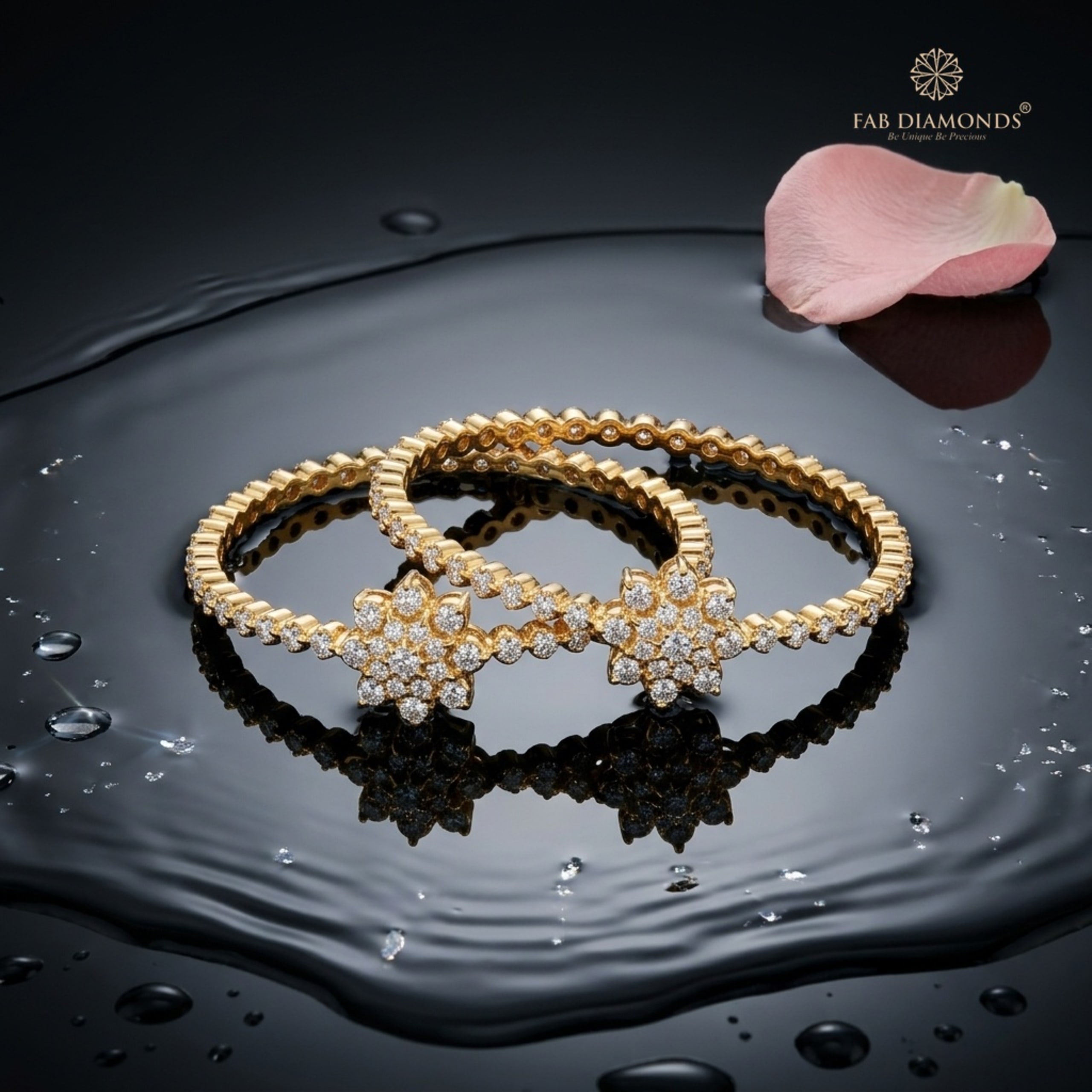 A pair of 18KT gold bangles with diamond star-burst motifs along the band