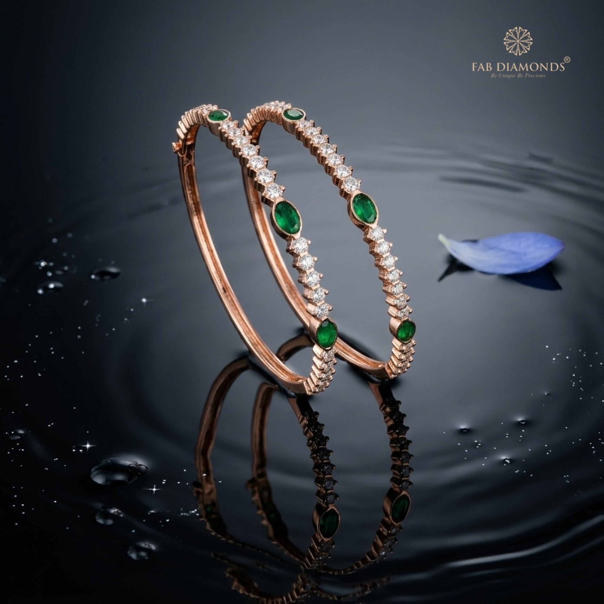 A pair of slim 18KT gold bangles with bezel-set emeralds and prong-set diamonds