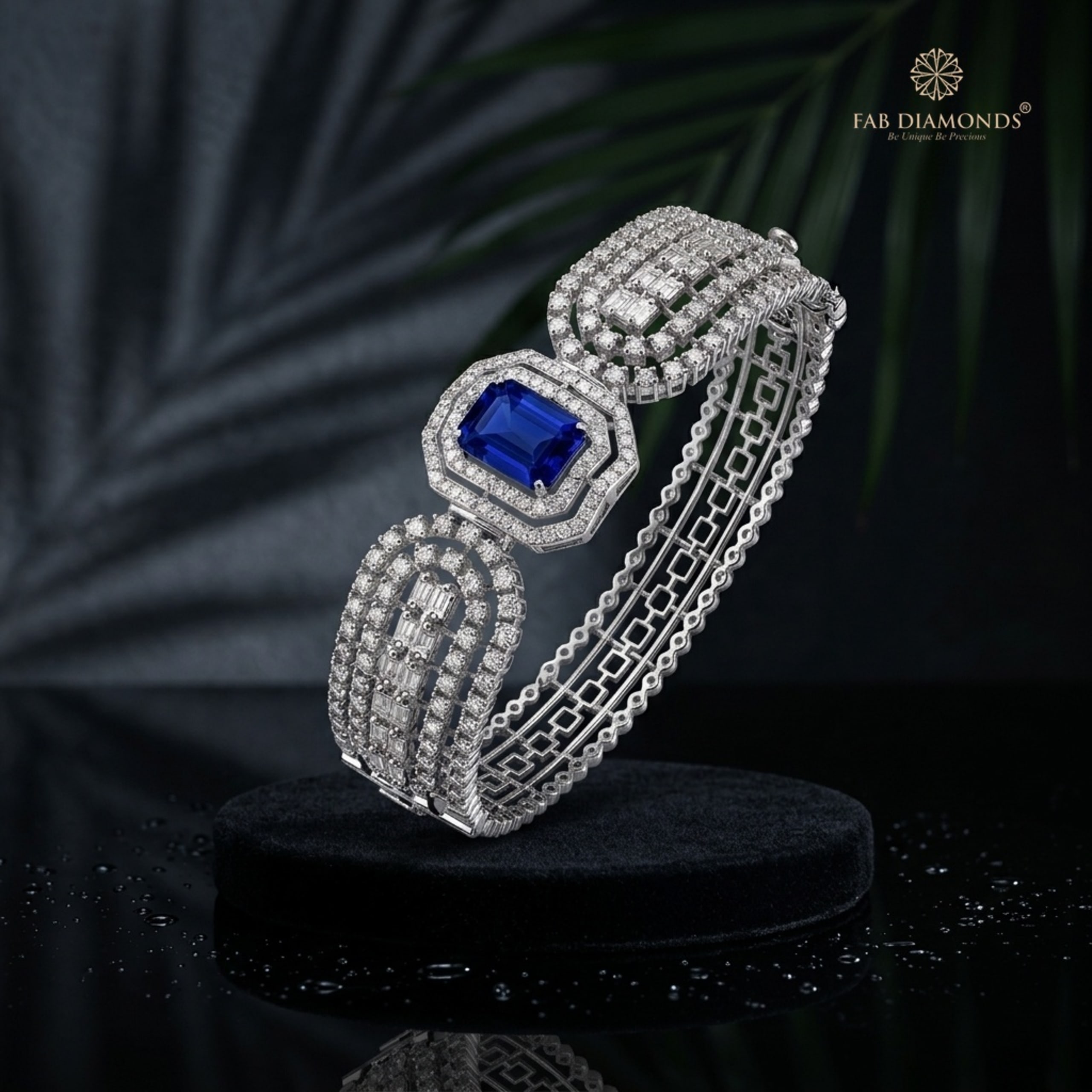 An 18KT white gold cuff with a royal blue sapphire center and tiered diamond baguette rails