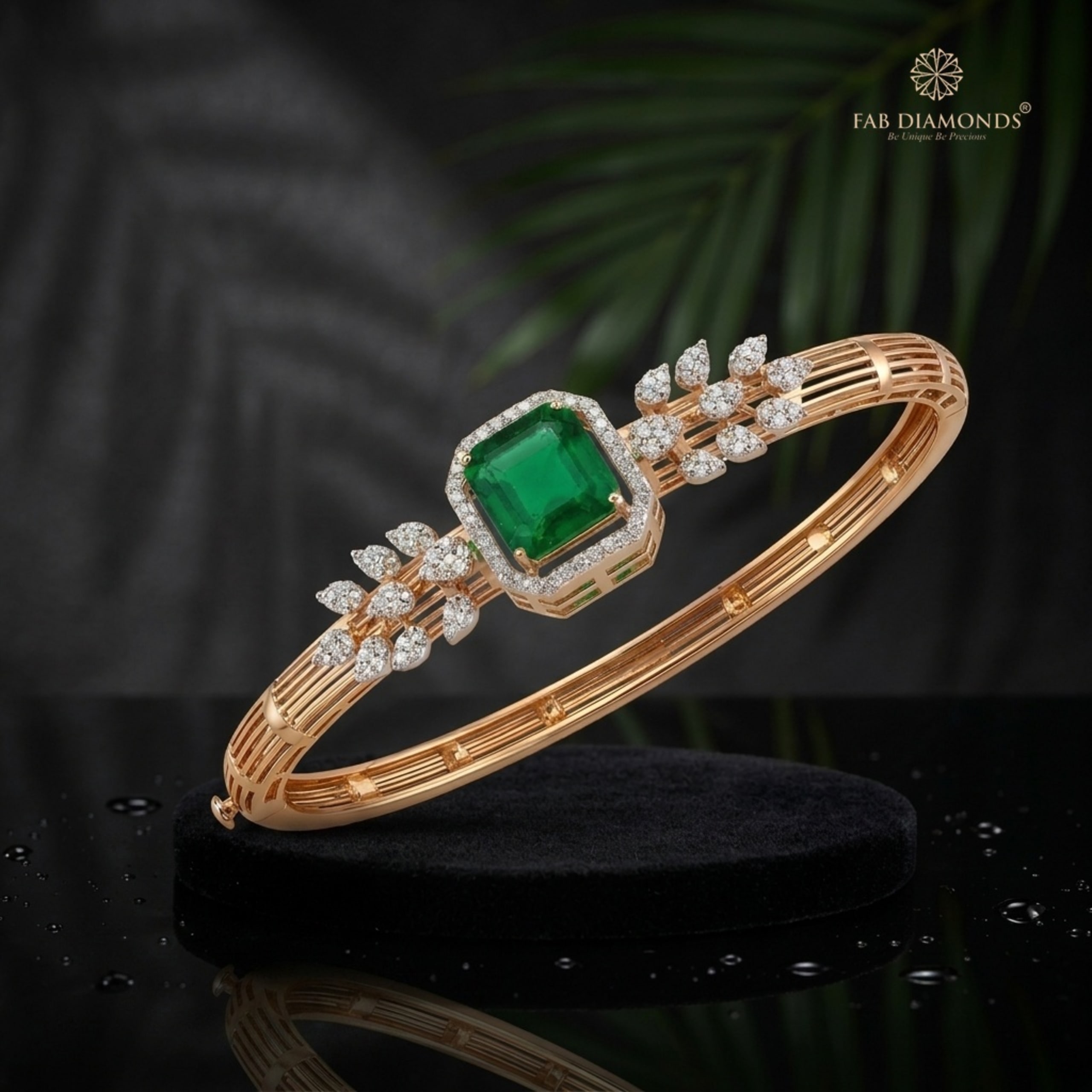 An 18KT rose gold bypass bangle with an octagonal emerald and marquise diamond leaves