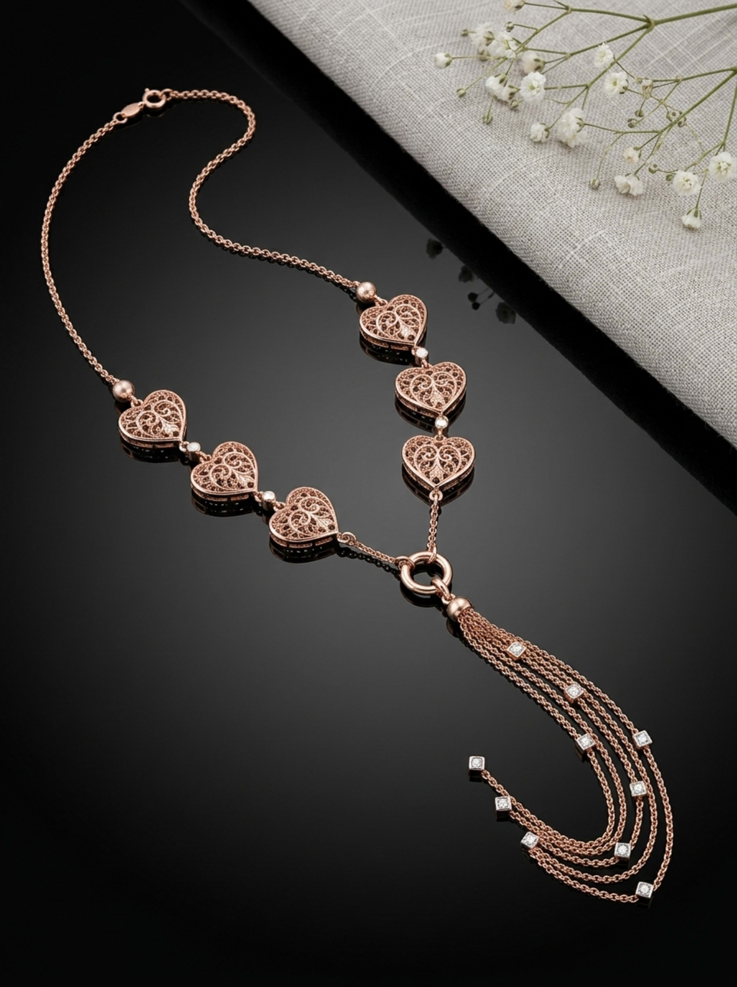 Filigree Heart Station Waterfall Lariat Chain in 18KT rose gold on glossy black surface